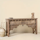 Side angle image of a hand-carved console table made from reclaimed teak wood, featuring intricate traditional Indian carvings and natural aged finish.