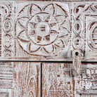 Close up image of a grey-washed reclaimed wood cabinet with hand-carved floral and sunburst detailing, a vintage furniture piece perfect for rustic or bohemian interiors.