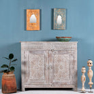 Grey-washed reclaimed wood cabinet with hand-carved floral and sunburst detailing, a vintage furniture piece perfect for rustic or bohemian interiors.