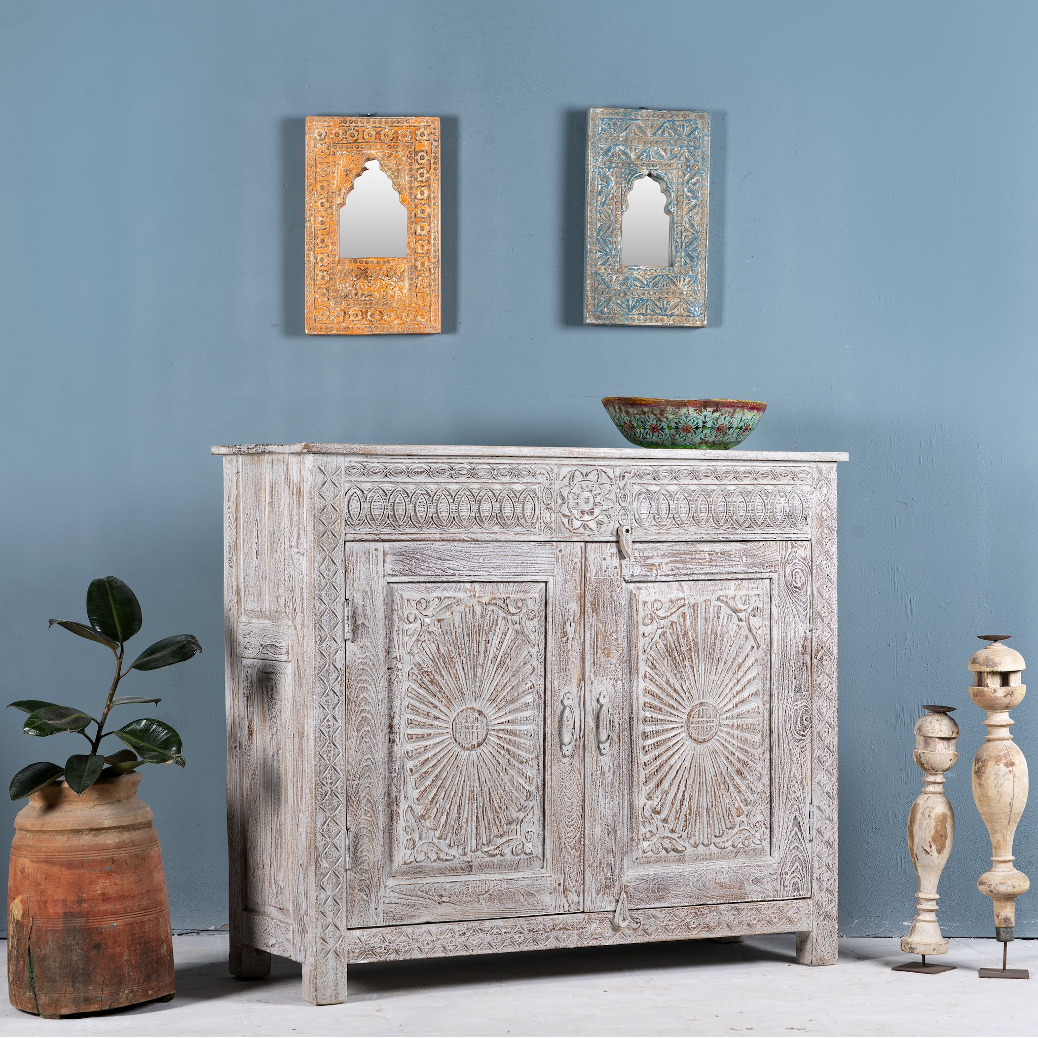 Side angle image of a grey-washed reclaimed wood cabinet with hand-carved floral and sunburst detailing, a vintage furniture piece perfect for rustic or bohemian interiors.