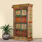 Side angle image of a and-painted teak wood cabinet with floral motifs; teak wood furniture for bohemian interiors, 105 × 55 × 177 cm.