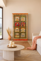 Lifestyle image of a hand painted teak wood cabinet with floral motifs, restored Indian furniture online; unique storage piece, 100 × 44 × 185 cm.