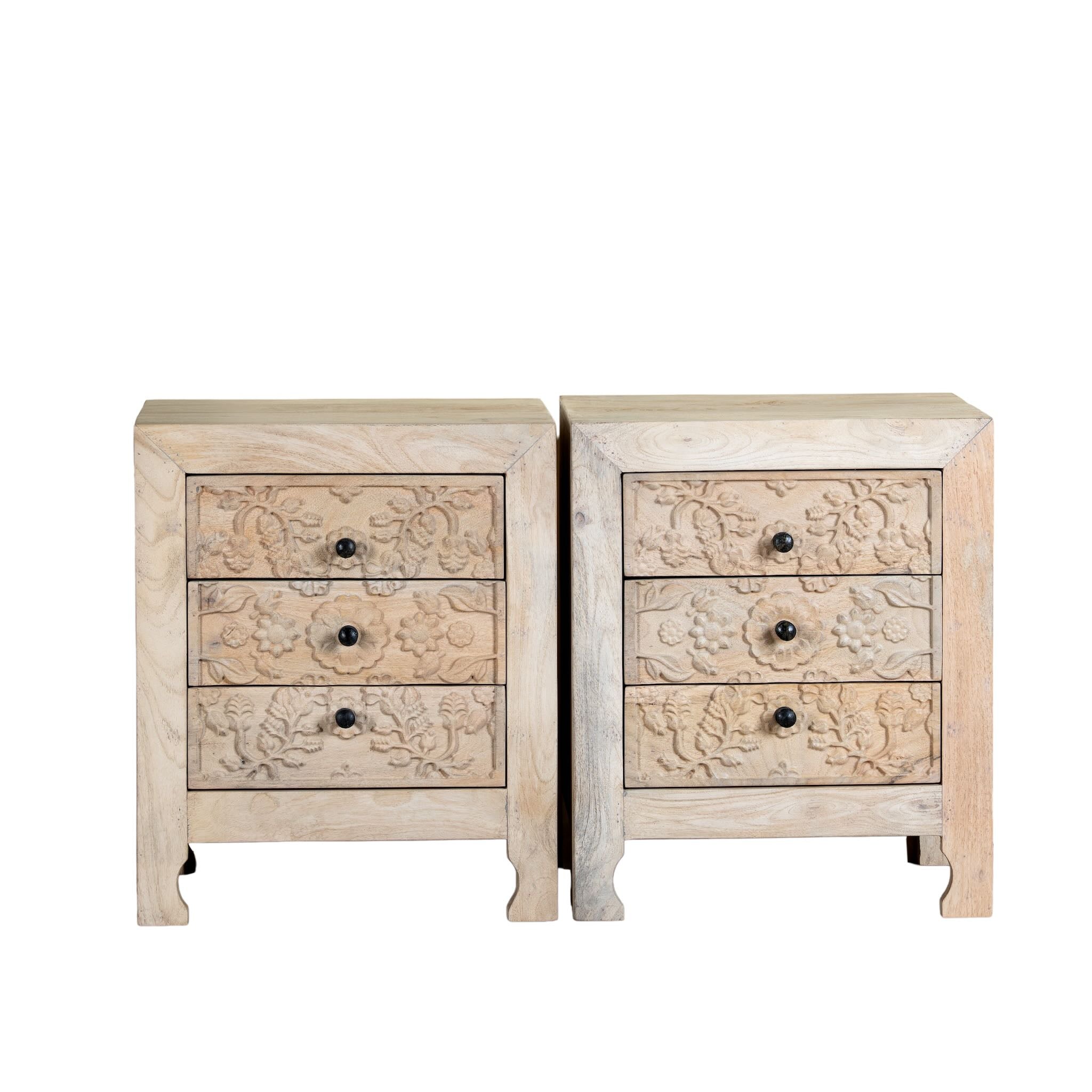 White background image of a pair of mango wood nightstands Vihaan with hand-carved floral drawer fronts and a natural distressed finish. Elegant vintage-style bedside tables offering both storage and artisan-crafted detail.