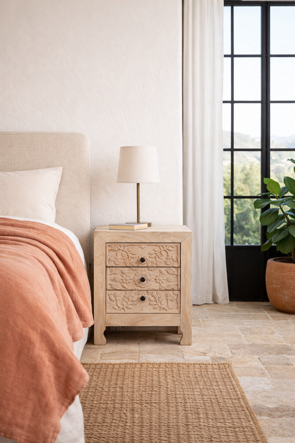Lifestyle imagination of a pair of mango wood nightstands Vihaan with hand-carved floral drawer fronts and a natural distressed finish. Elegant vintage-style bedside tables offering both storage and artisan-crafted detail.