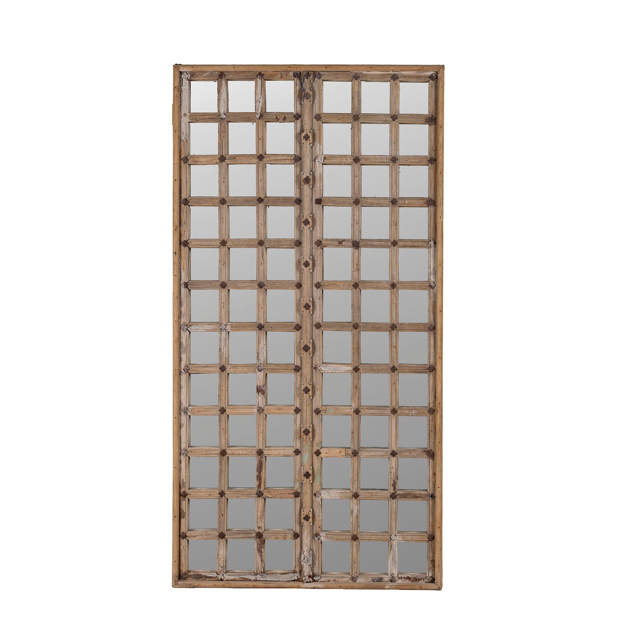White background picture of a wall mirror crafted from an old teak window frame with a fine grid of small mirrored panes and rustic metal accents, blending heritage with minimalist design.