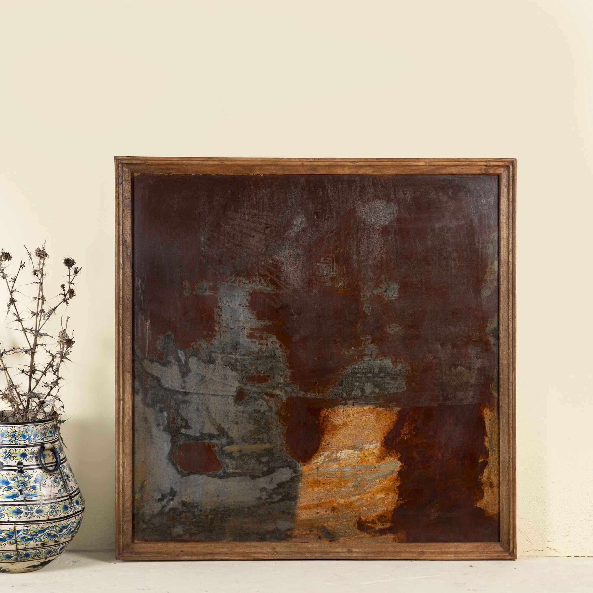 Live style picture of a decorative wall panel featuring naturally rusted metal with a reclaimed teak wood frame, showcasing an abstract, earthy patina finish.

