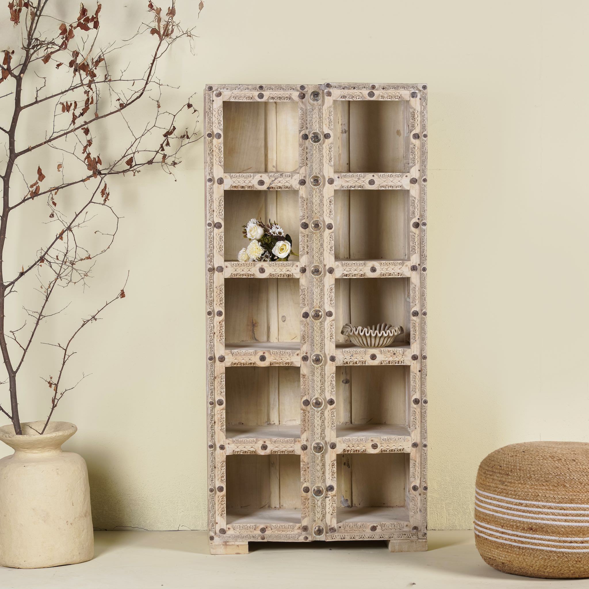 A handcrafted reclaimed teak wood shelf with iron fittings, featuring multiple compartments and placed against a neutral background with decorative items on it.