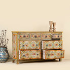 Side angle image with open drawers of a Ziya hand‑painted chest of 8 drawers made from reclaimed wood with floral motifs and iron handles—an artisan piece of painted wooden furniture.