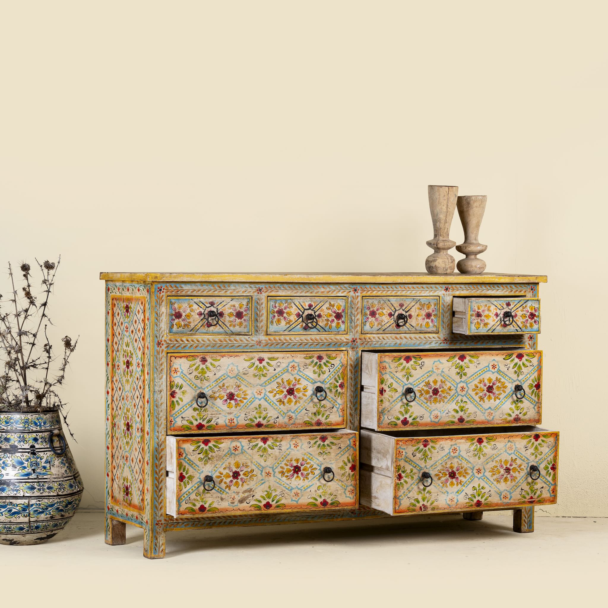 Side angle image with open drawers of a Ziya hand‑painted chest of 8 drawers made from reclaimed wood with floral motifs and iron handles—an artisan piece of painted wooden furniture.