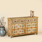 Side angle image of a Ziya hand‑painted chest of 8 drawers made from reclaimed wood with floral motifs and iron handles—an artisan piece of painted wooden furniture.