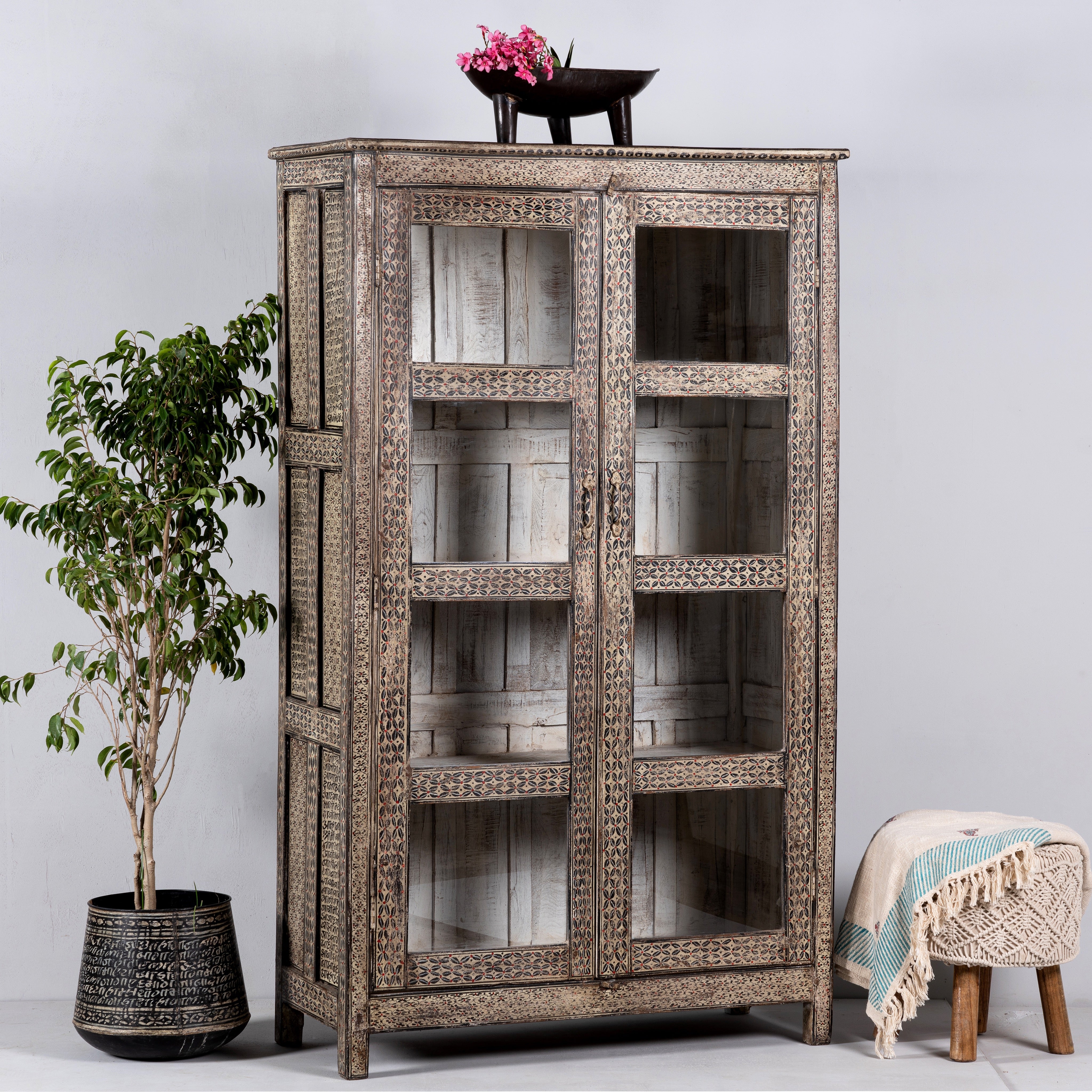 Side angle image of a handcrafted display cabinet made from reclaimed Teak wood with glass doors and Sanskrit motifs; sustainable and unique wooden furniture, 182 × 93 × 42 cm.