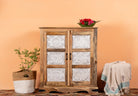 A handcrafted Indian cupboard made of natural mango wood with white floral engravings on the front, two doors, and a decorative item on top.