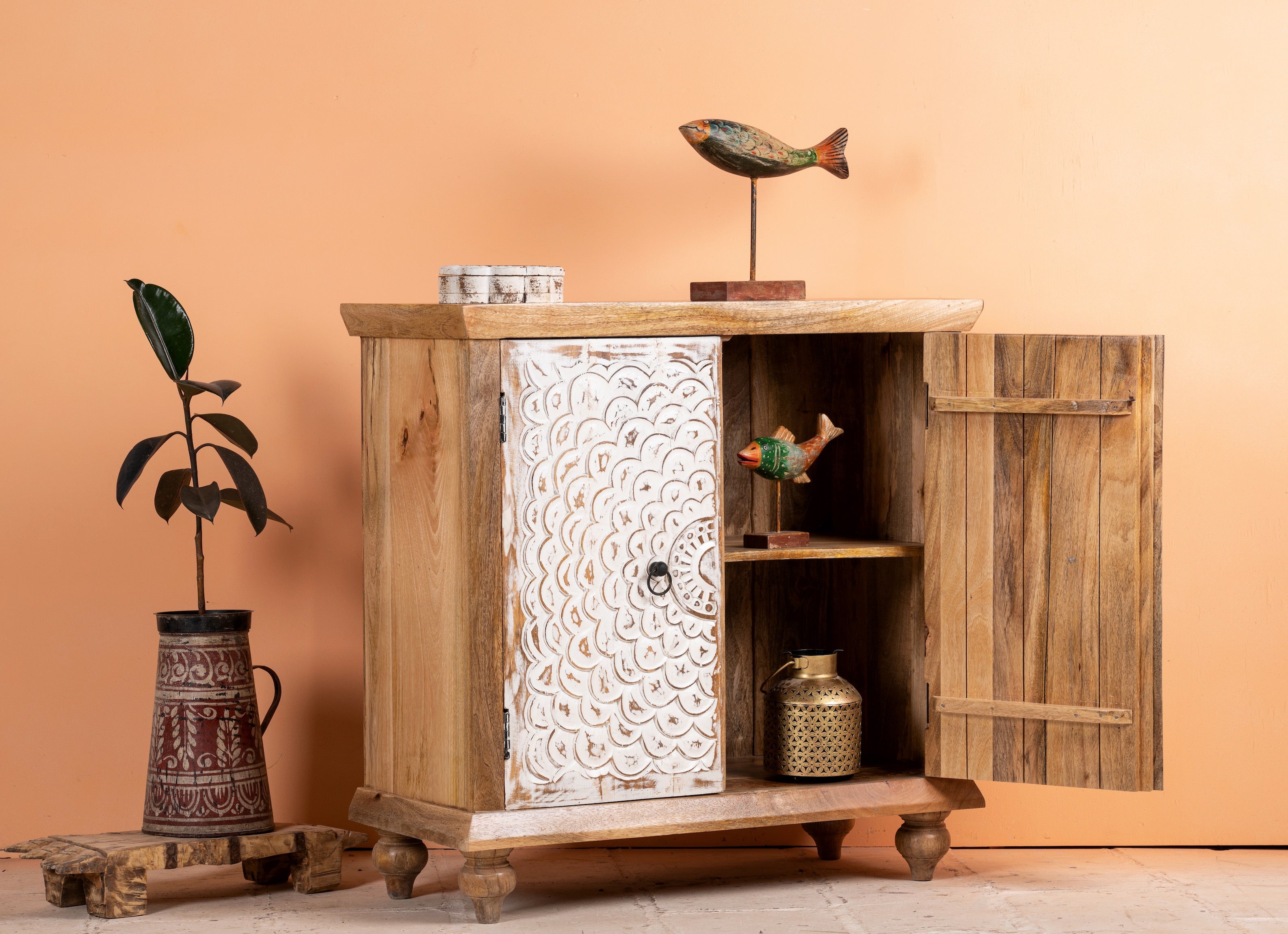 Side angle image with open door of a carved wood furniture cupboard with white-washed engraved doors and mango wood body, 90 × 90 × 40 cm.