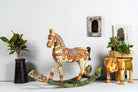 Side angle image of a hand-painted mango wood rocking horse “Gita” in Rajasthani style – colourful Indian home accessory and mango wood decor piece, 104x78x30cm.