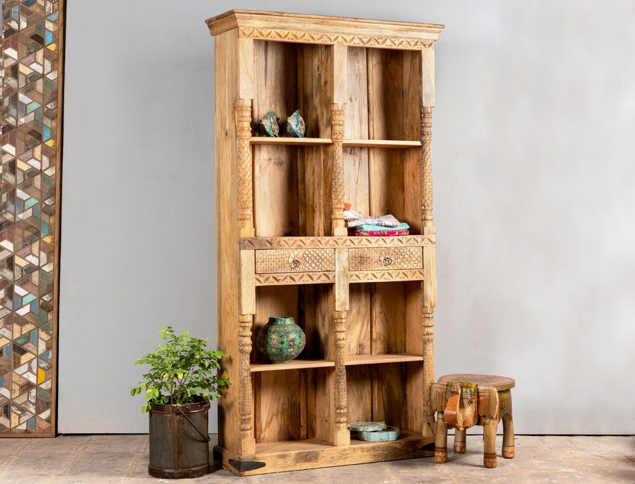 Side angle image of a handcrafted mango wood bookshelf with carved detailing – mango wood shelving and carved wooden furniture in a warm brown finish for timeless interiors.