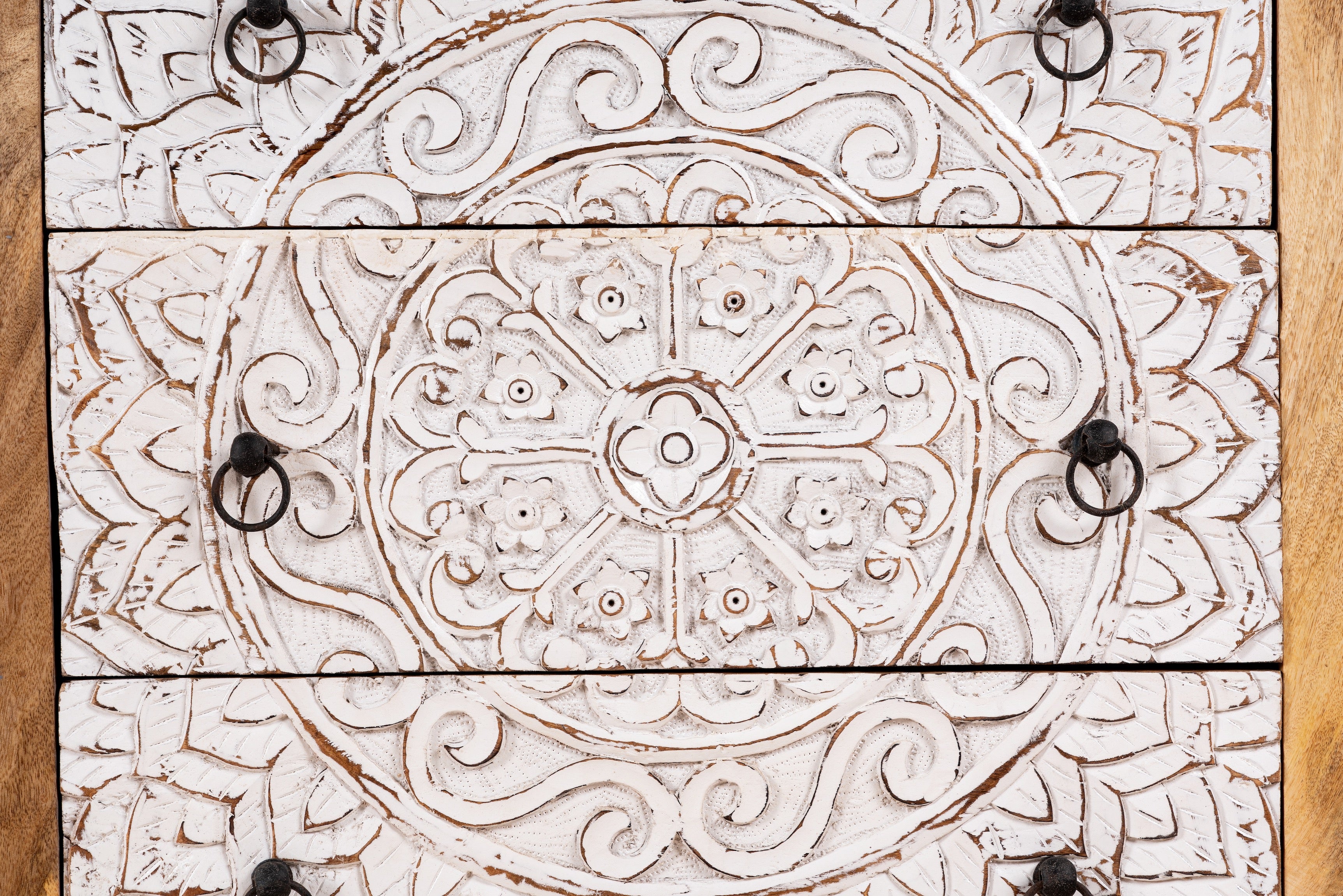 Close up image of a mango wood carved chest of drawers with whitewashed floral engraved fronts, 80 × 40 × 90 cm.