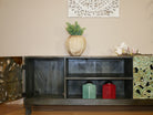 Open door image of a carved mango wood lowboard with green floral doors, black frame, and open shelving, 150 × 60 × 40 cm.
