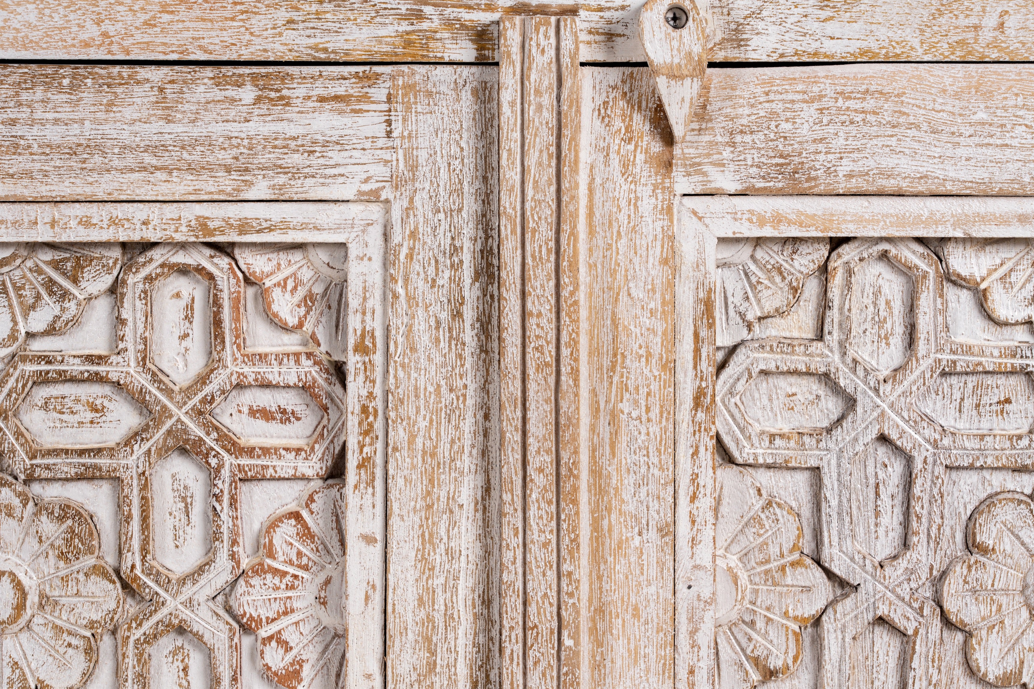 Close up image of a white washed cabinet handcrafted from mango wood with engraved doors; artisanal Indian mango wood furniture, 90 × 90 × 40 cm.