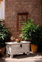 Lifestyle image in a garden with a hand‑carved mango wood chest with floral detailing – vintage home accessories and artisan storage chest for stylish interiors.