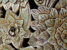 Close up image of a carved mango wood lowboard with green floral doors, black frame, and open shelving, 150 × 60 × 40 cm.