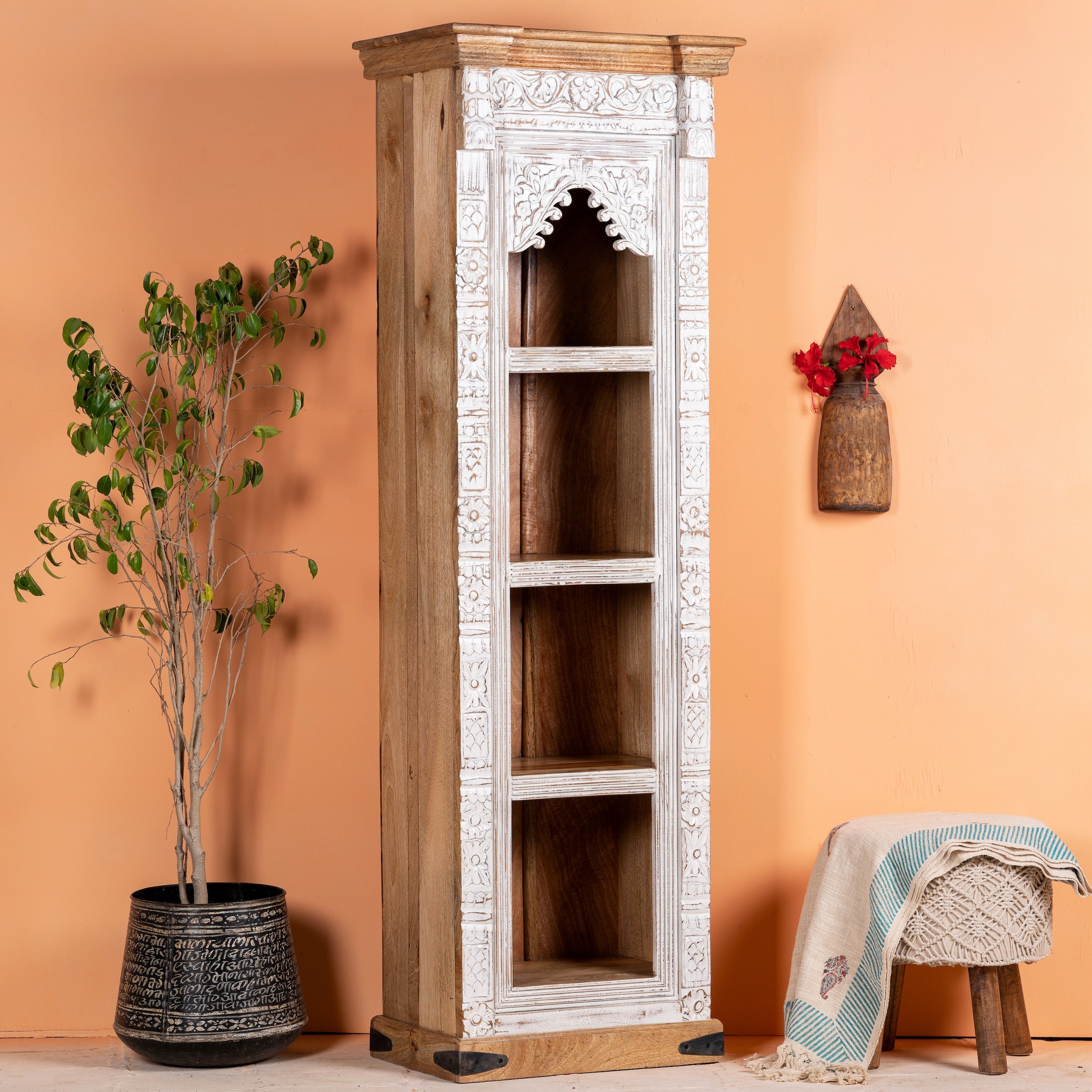 Side angle image of a hand carved white washed mango wood bookshelf with Mediterranean design – narrow wooden furniture piece with decorative carving and natural charm.