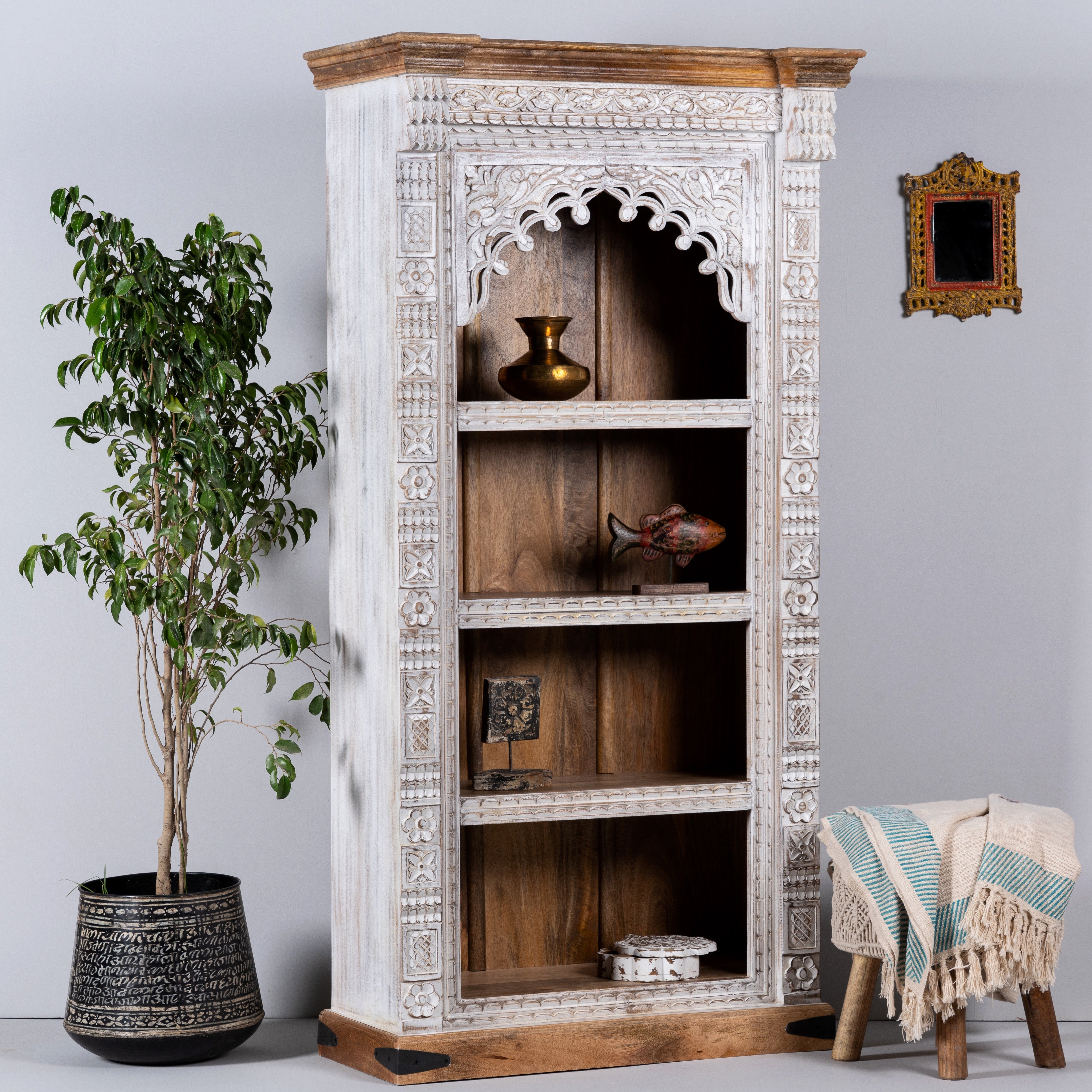 Side angle image of a hand-carved mango wood bookshelf with arched frame and whitewashed finish – carved wooden furniture and mango wood shelving with Indian-inspired design.