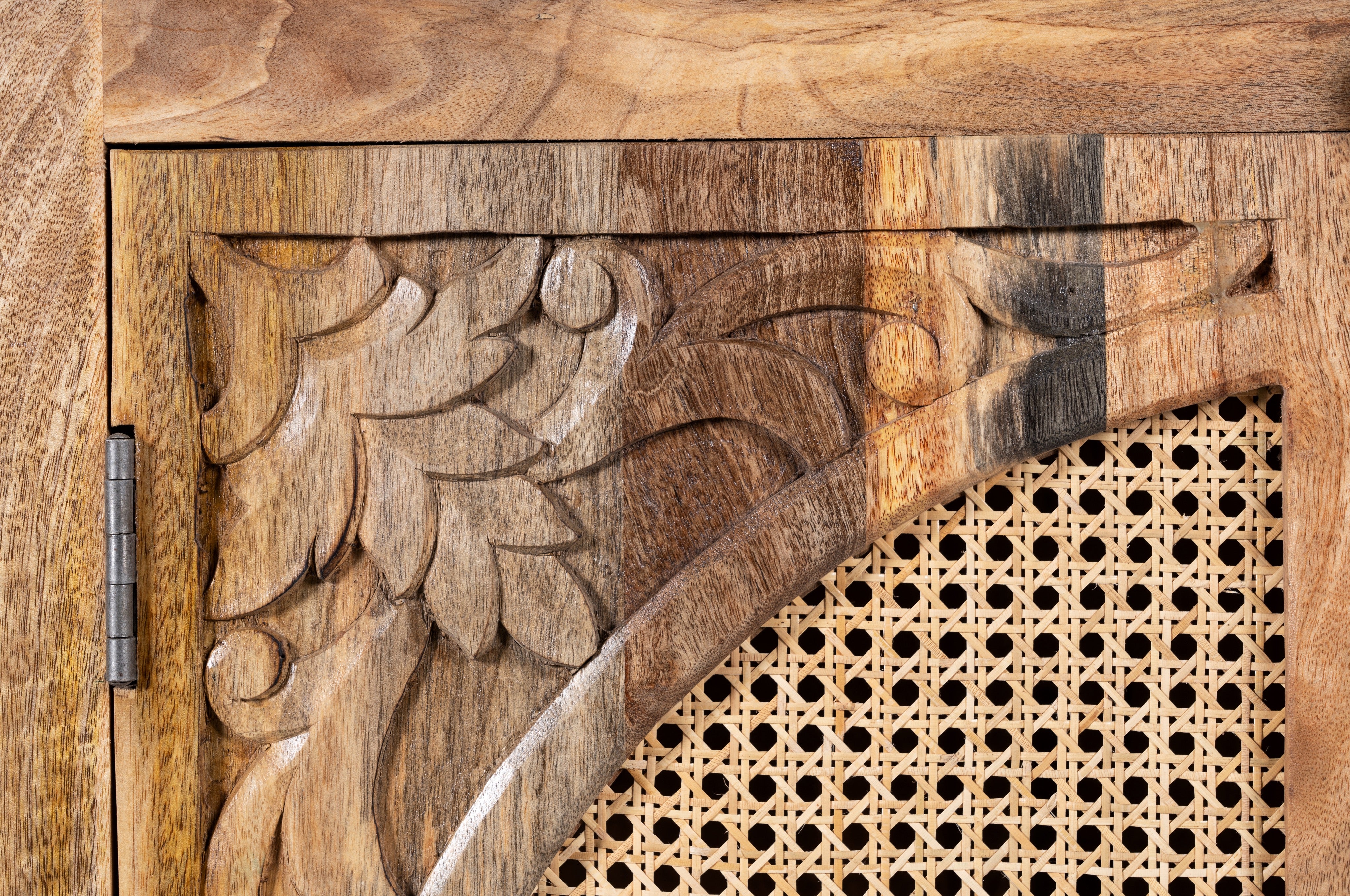 Close up image of a mango wood cupboard with rattan door panels and hand‑carved Indian ornamentation, 80 × 40 × 104 cm.