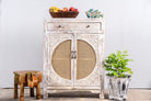 White‑washed mango wood cupboard with rattan door panels and hand‑carved Indian ornamentation, 80 × 40 × 104 cm.